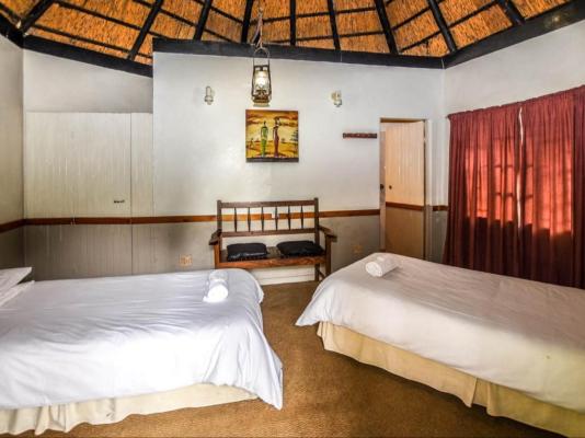 Inside a rondavel: two beds made up under the thatched roof