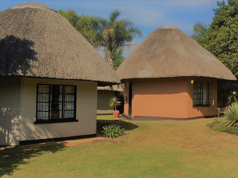 A thatched rondavel with its own entrance, set among established garden